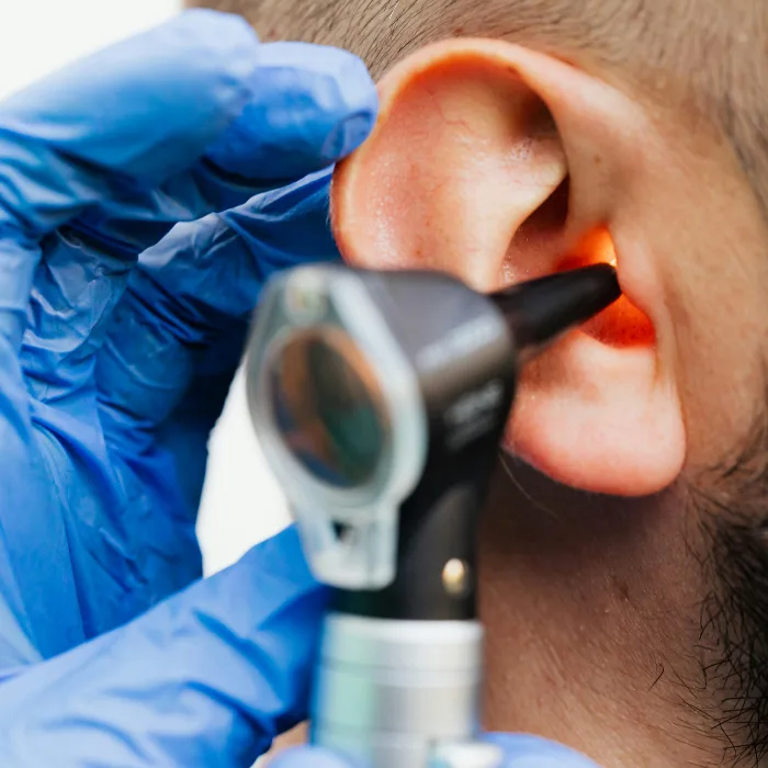 Audiologist carrying out ear wax removal during a clinic appointment